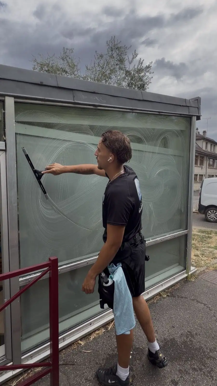 Arthur de BlueOtter nettoyant une vitre à la raclette